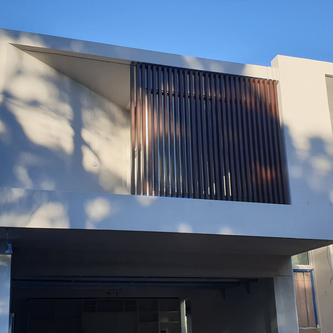 Dark vertical-slat metal privacy screen set into a contemporary facade