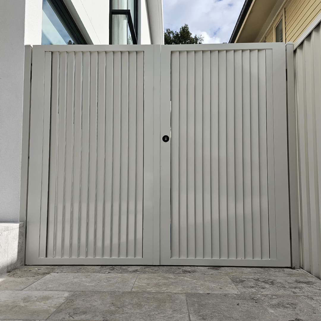 Pair of custom white louvered aluminium gates on a contemporary home