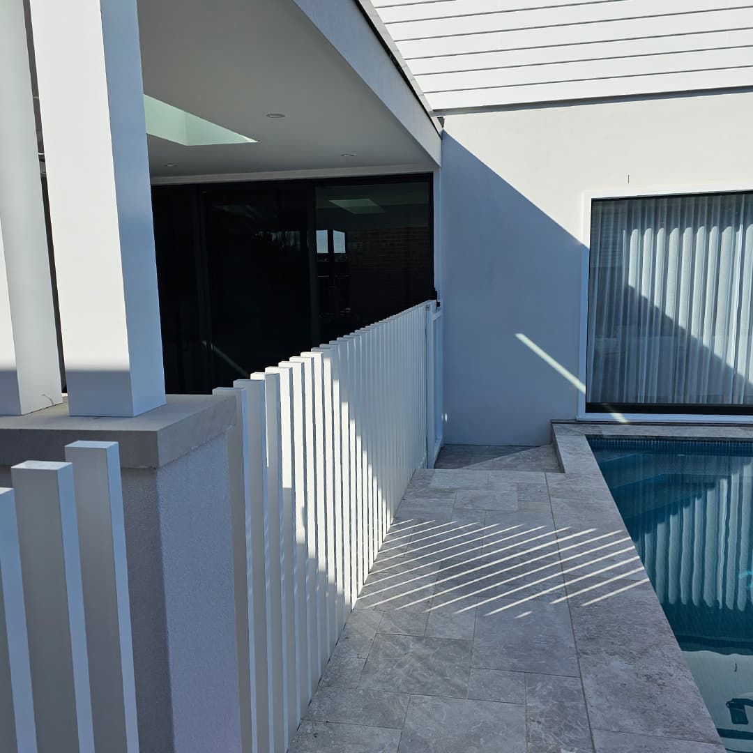 White aluminium slat pool fencing beside a residential swimming pool