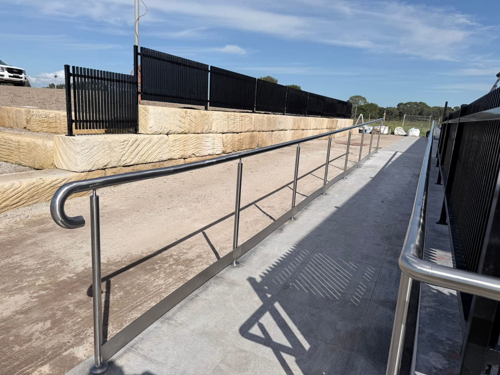 Polished stainless steel handrails on an outdoor accessibility ramp