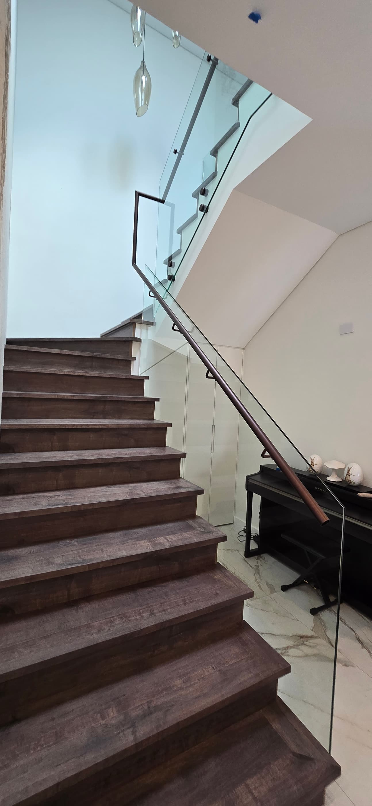 Curved timber staircase with frameless glass balustrade and black handrail