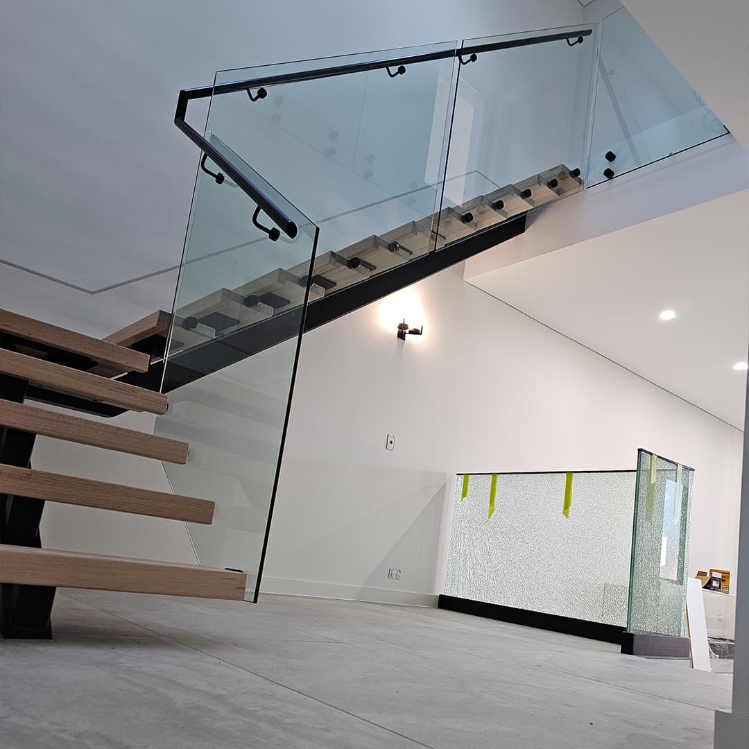 Open-riser timber staircase on a black steel stringer with glass balustrade